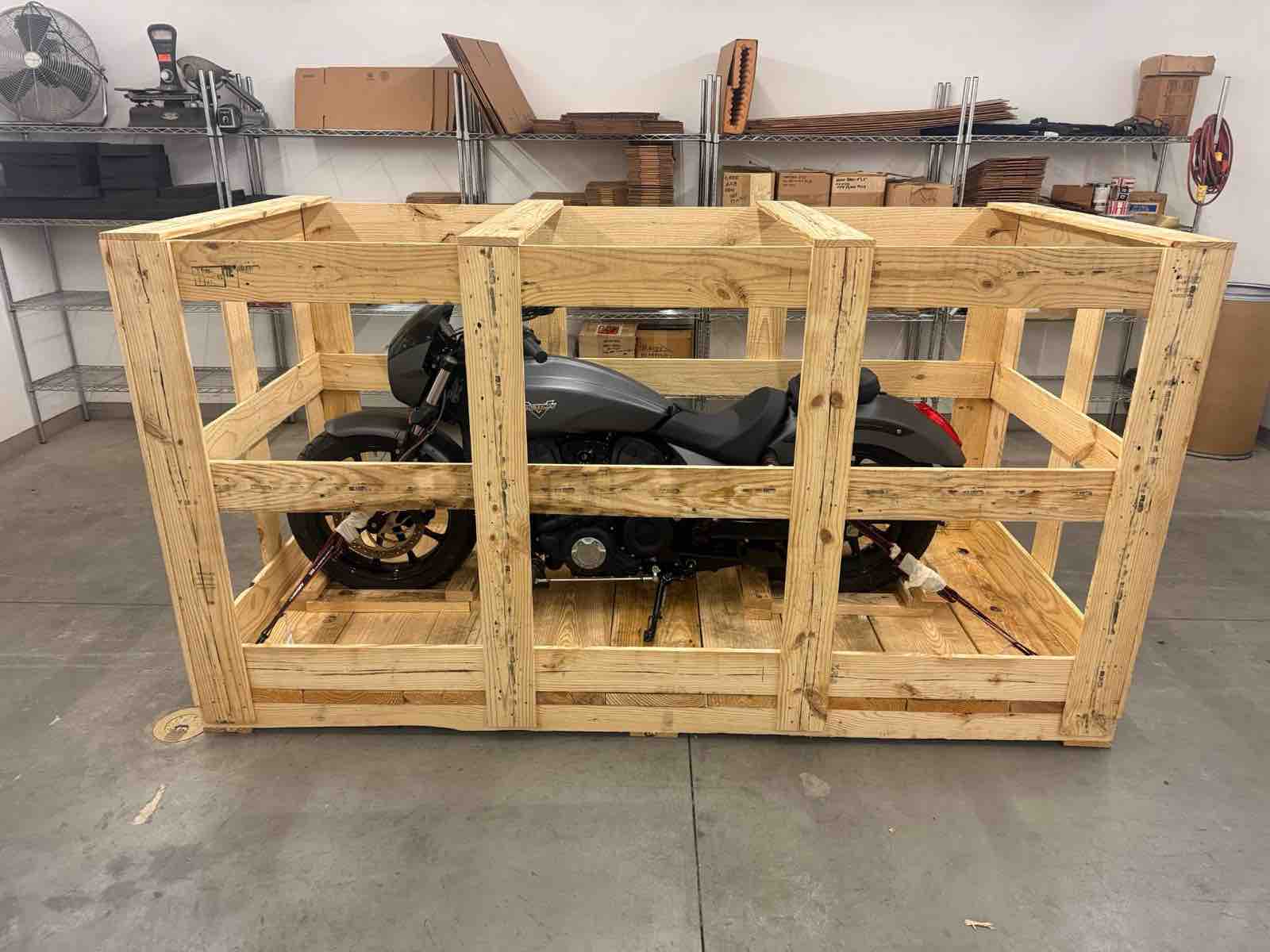 Motorcycle strapped down inside an open wooden shipping crate