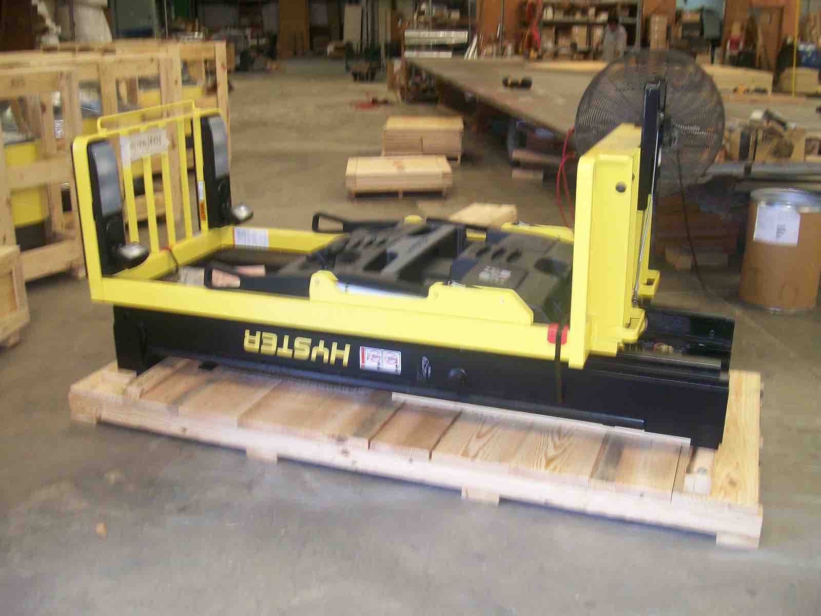 Yellow industrial equipment strapped to a custom wooden skid